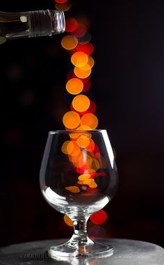 a wine glass is being filled with red, orange and yellow bubbles in the dark