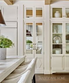 a kitchen with white cabinets and glass doors