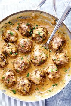 a pan filled with meatballs covered in gravy and garnished with parsley