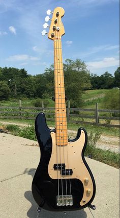 a black bass guitar sitting on top of a sidewalk