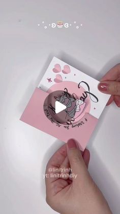 someone holding up a pink card with a cat on it