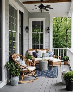 a porch with wicker furniture and potted plants on the front porch, along with an area rug