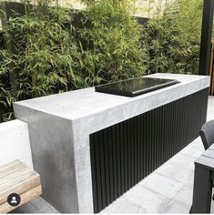 a modern outdoor bar in the middle of a patio with bamboo trees and bushes behind it