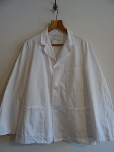 Vintage white cotton drill British work jacket.   Deadstock when acquired but has been laundered to freshen it up.  Circa 1970s, made by Pexwear- note that the maker's label has faded away completely with laundering.   Marked a vintage size 42".  Its 23 1/2" pit to pit. Please check the measurements below.  We no longer accept returns on the basis of items not fitting.  White 100% cotton with open revers and three button fastening, patch pockets.  Simple unlined style cut boxy and wide for worki Vintage White Shirt For Workwear, Vintage Lab Coat, Vintage Cotton Outerwear With Notch Lapel, Vintage White Cotton Outerwear, White Vintage Cotton Outerwear, Vintage White Windbreaker With Pockets, Chore Jacket, Cotton Coat, Work Jackets