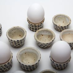 nine cups with eggs in them sitting next to each other on a white table top