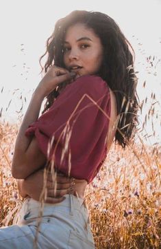 a woman standing in tall grass with her hands on her chest