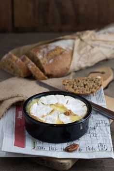 a bowl of food sitting on top of a table next to bread