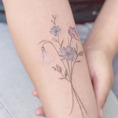 a woman's arm with flowers on it and a small tattoo behind the arm