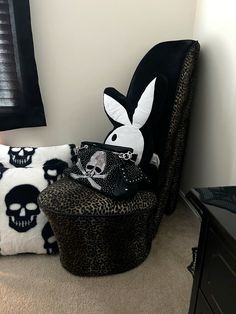 a black and white chair sitting next to a skull pillow on top of a leopard print ottoman