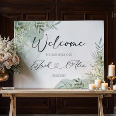 a welcome sign sitting on top of a wooden table next to candles and vases