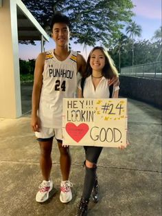 two people standing next to each other holding a sign that says hey lookin good