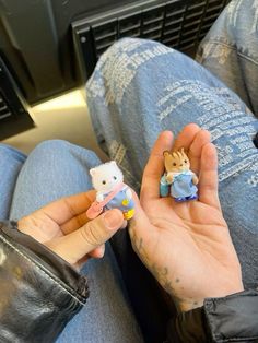 someone is holding two small stuffed animals in their hands while they are sitting on the floor