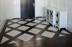 a white cabinet sitting on top of a hard wood floor next to a black door