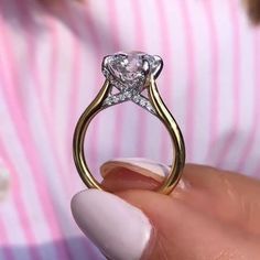 a close up of a person's hand holding a ring with a diamond on it