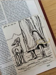 an open book with a drawing of two sheep standing next to each other on top of a wooden table