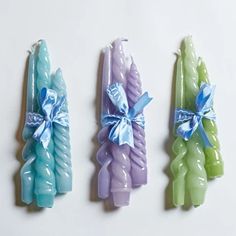 three different colored candles with bows on them