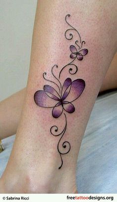 a woman's leg with a tattoo on it that has purple flowers and swirls