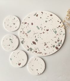 three white plates sitting on top of a table next to a vase with flowers in it