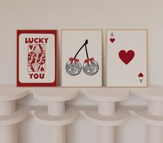 three cards are hanging on the wall next to each other, one has a pair of cherries