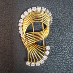 Description: Cartier A French 1950's 18K Gold Brooch with Diamonds by Cartier...This highly stylized brooch appears to be caught in  motion as a bouquet of gold ribs. Makes an elegant diamond crowned arc before looping back upon itself ultimately fanning out as it stretches downward allowing for the significant diamond accents at the top & bottom of the brooch to  be displayed in full. Solid 18K Yellow & White Gold (Platinum) with 23 Near Perfect Round Brilliant Cut Diamonds prong mounted with t Vintage Cartier Jewelry For Evening, Vintage Cartier Diamond Jewelry, Diamond Yellow Gold Brooch For Anniversary, Anniversary Diamond Brooch In Yellow Gold, Anniversary Yellow Gold Diamond Brooch, Yellow Gold Diamond Brooches For Formal Occasions, Formal Yellow Gold Diamond Brooch, Formal Yellow Gold Diamond Brooches, Gold Diamond Brooch For Anniversary