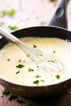 a pan filled with cheese and parsley being whisked