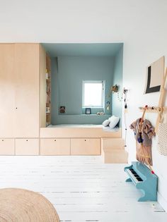 a bedroom with white flooring and blue walls in the background, there is a piano on the wall