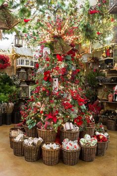 a christmas tree in a store with many baskets around it and presents under the tree