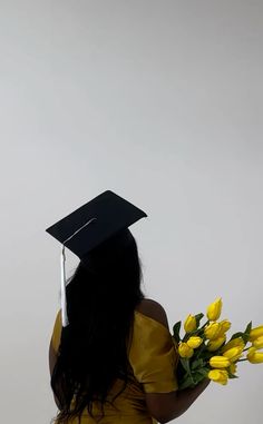 a woman wearing a graduation cap and gown holding yellow flowers