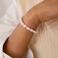 a close up of a person wearing a white bracelet with pearls on the end of it