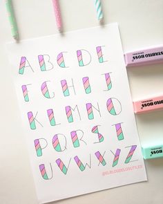 the letters and numbers are drawn on paper with colored pencils next to them,