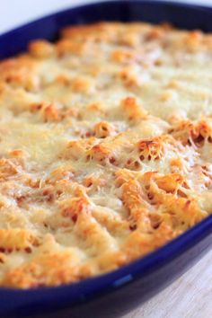 a casserole dish with cheese and meat in it sitting on a wooden table