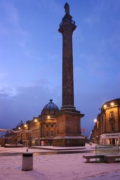 a large monument in the middle of a snowy street at night with lights on it