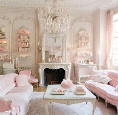 a living room filled with furniture and a chandelier hanging from the ceiling over a fire place