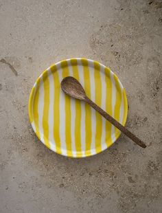 a yellow and white striped plate with a wooden spoon