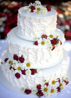 a three tiered cake with white frosting and flowers