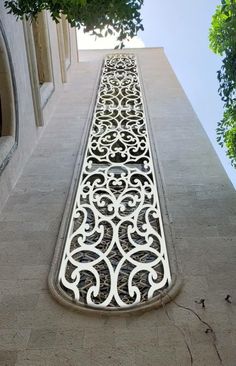 an intricate ironwork on the side of a building with trees growing out of it