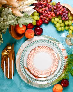 the table is set with plates, silverware and fruit