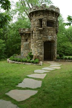 a stone tower with a gate in the grass