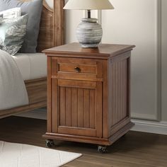 a wooden night stand with a lamp on top