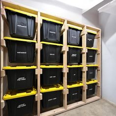 several bins are lined up on shelves in a storage room with yellow and black containers