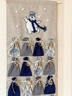 a wall hanging with blue and white bags on it's side, which has an image of a snowman in the middle