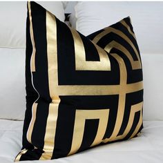 a black and gold pillow sitting on top of a white bed