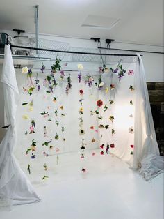 a white backdrop with flowers hanging from it's sides and curtains in the background