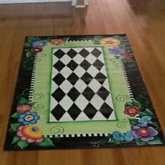 a black and white checkerboard floor mat with flowers on the bottom, in front of a door