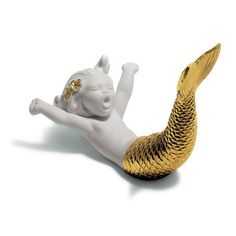 a white and gold mermaid figurine laying on its back