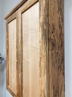 a large wooden cabinet sitting on top of a white wall next to a light fixture