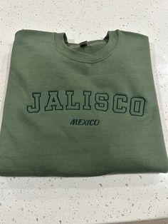 Jalisco Mexico Embroidered Crewneck Sweatshirt Casual Tops With Custom Embroidery For College, Green Casual Sweatshirt With Embroidered Text, Casual Green Sweatshirt With Embroidered Text, Casual Embroidered Crew T-shirt, Casual Short Sleeve Sweatshirt With Custom Embroidery, Casual Short Sleeve Sweatshirt With Embroidered Text, Embroidered Crewneck, Fun Sweatshirts, Kansas City Mo