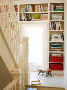 a room with bookshelves and stairs leading up to the second floor in this home