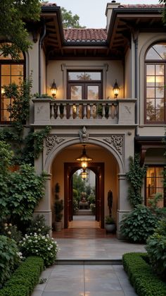 an entrance to a large home surrounded by greenery