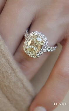 a close up of a person's hand with a yellow and white diamond ring